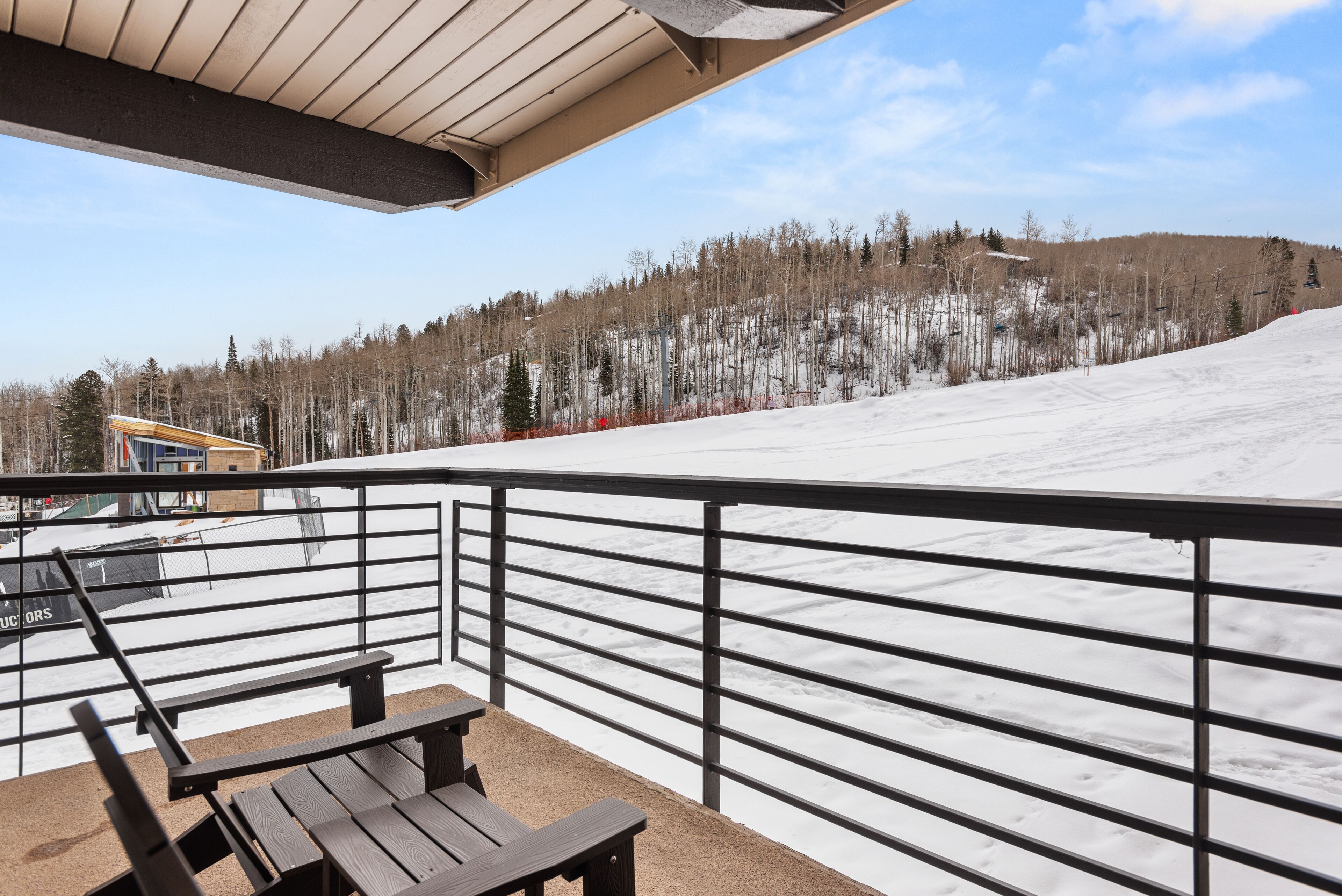 A balcony with a metal railing overlooking a snowy landscape and a distant building.