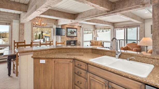 A spacious kitchen with granite countertops, wooden cabinets, and a large island with a sink. - Enclave 201 | Snowmass Ski-In/Ski-Out Condo w/Shared Pool/Hot Tub/Gym/WiFi (Snowmass Village)