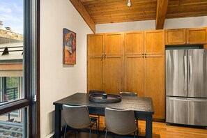 Une cuisine moderne avec des meubles en bois, un réfrigérateur en acier inoxydable et une table à manger avec des chaises.