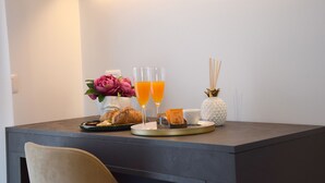 En morgenmadsopsætning med croissanter, appelsinjuice og en vase med blomster på et bord.