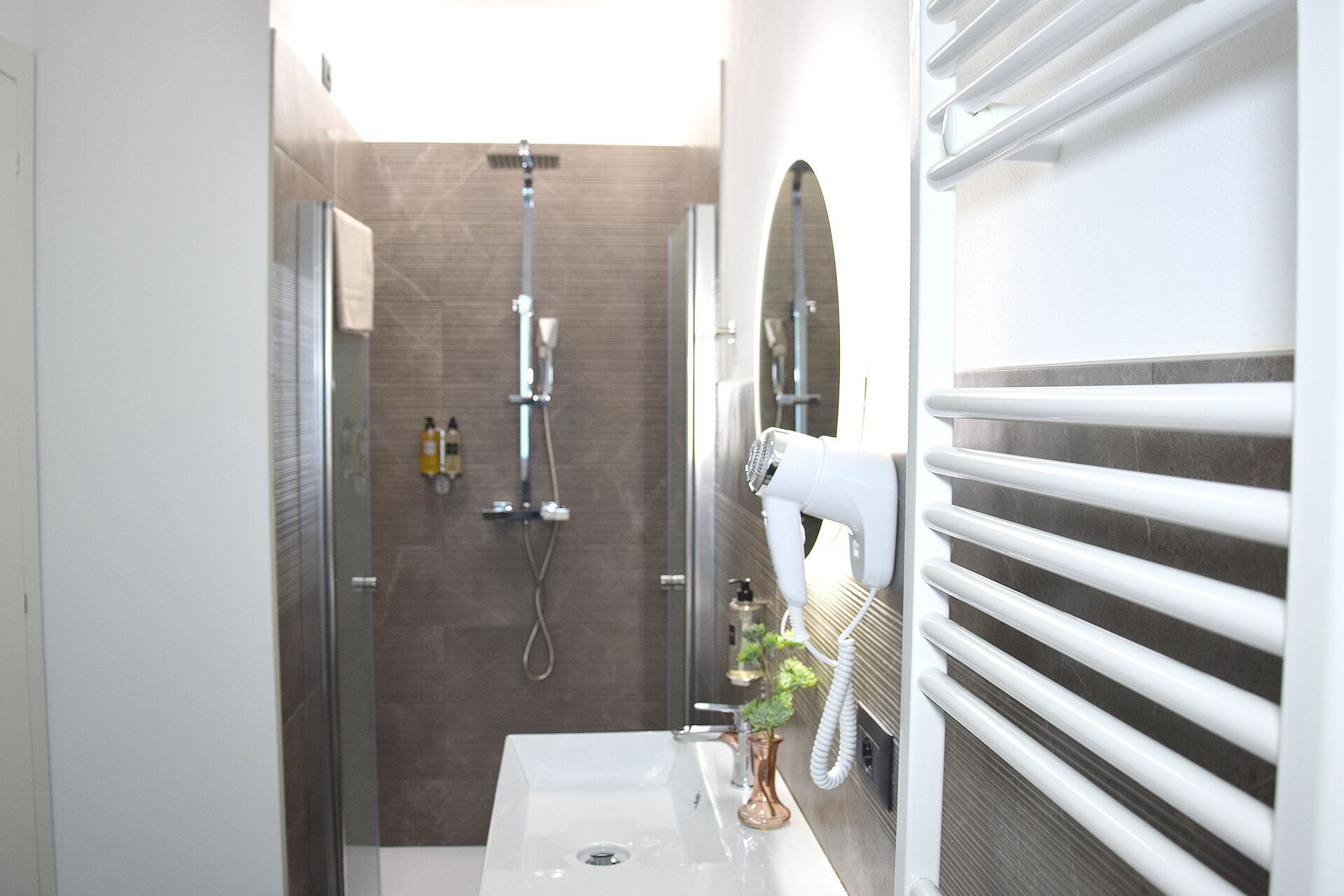 A modern bathroom with a shower, a white sink, and a hairdryer.