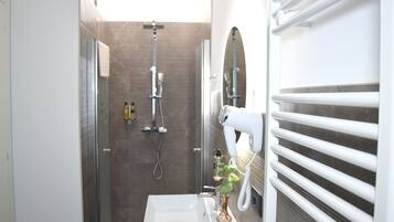 A modern bathroom with a shower, a white sink, and a hairdryer.