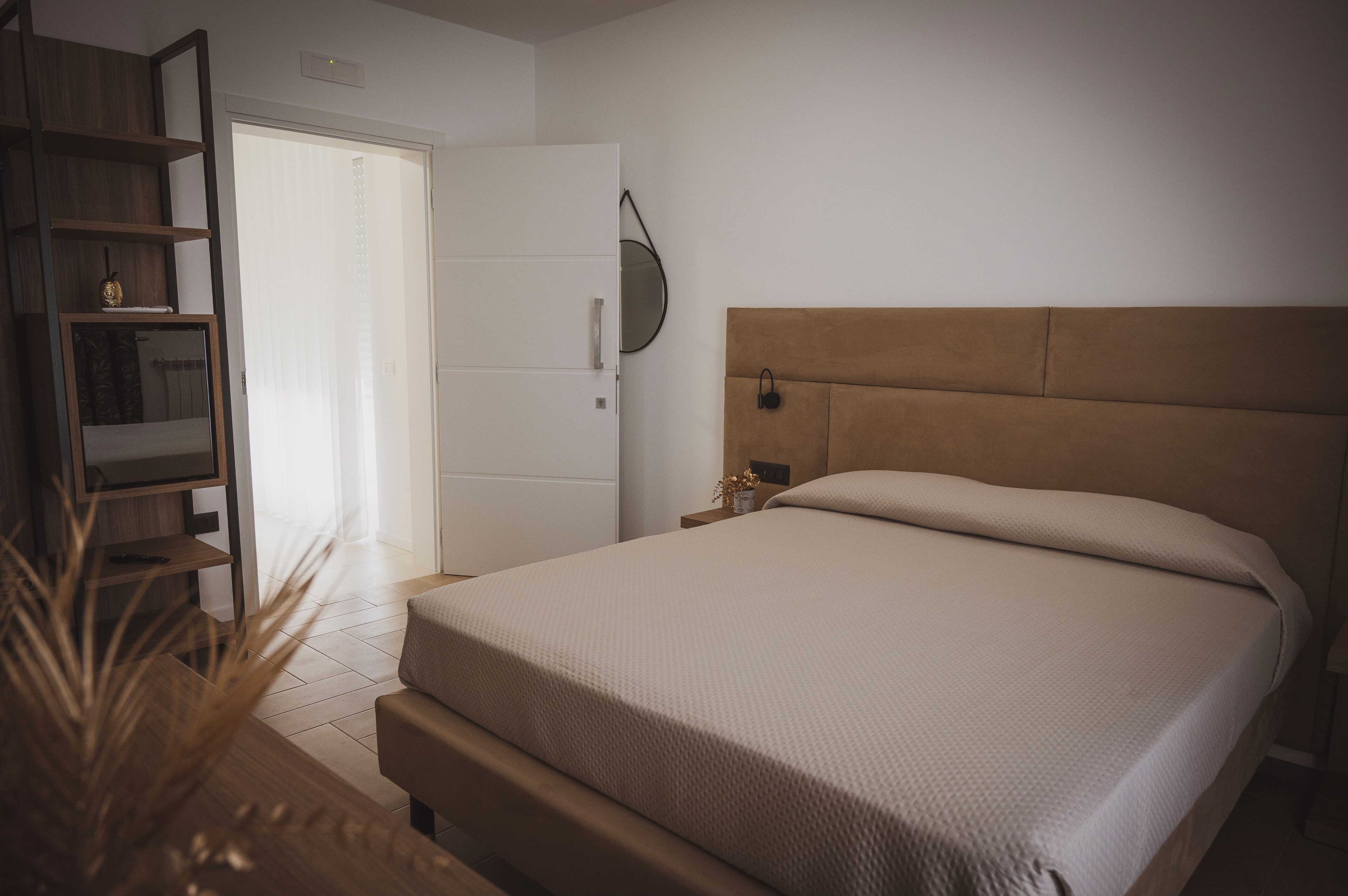 Ein Schlafzimmer mit einem Bett, einem Nachttisch aus Holz, einem Spiegel und einem Kleiderschrank.