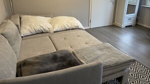 Ein sofas in neutralen Farben mit einer gepolsterten Rückenlehne und einem dunkelbraunen Zierkissen.