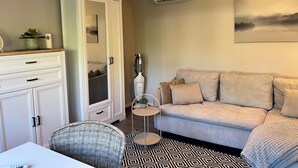 Ein modernes Wohnzimmer mit einer Couch, einem Schrank, einem kleinen Tisch und einem Sessel.