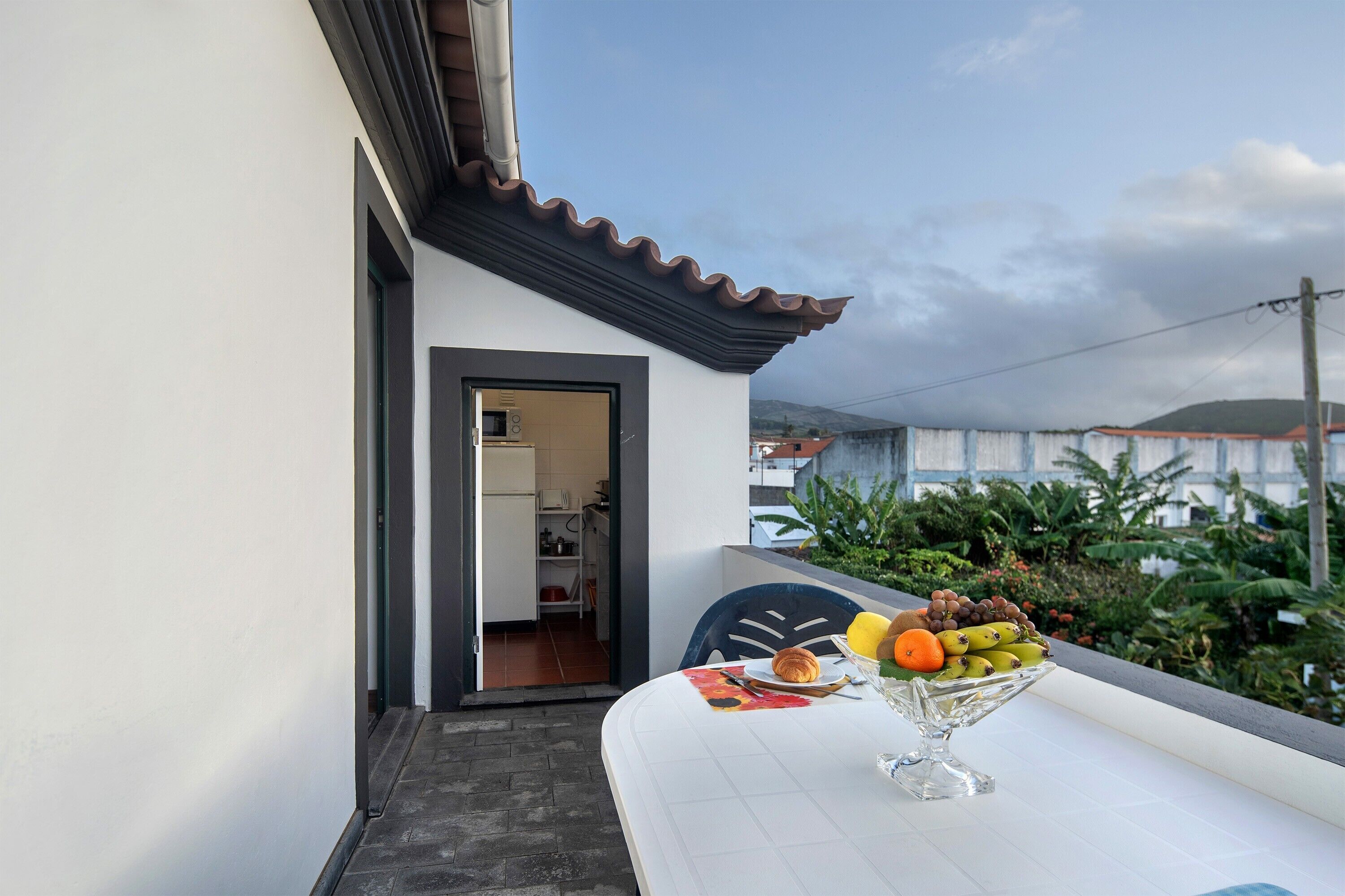 Varanda com mesa posta para o café da manhã, vista da cidade e porta que dá para um espaço interno.