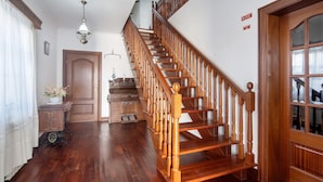 A wooden staircase with a handrail, a door with a glass panel, and a wall-mounted light fixture.