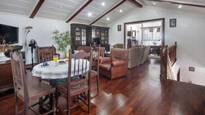 A dining area with a wooden table, chairs, and a ceiling with wooden beams.