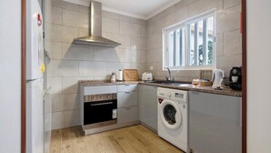 Une cuisine compacte équipée d’un four encastré, d’un lave-linge et d’une fenêtre.