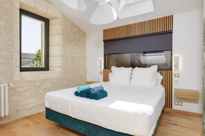 A modern bedroom with a large bed, wooden headboard, and a window with a view.