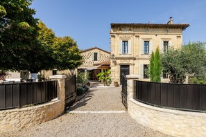 A traditional stone building with a gravel driveway leading to a gated entrance.