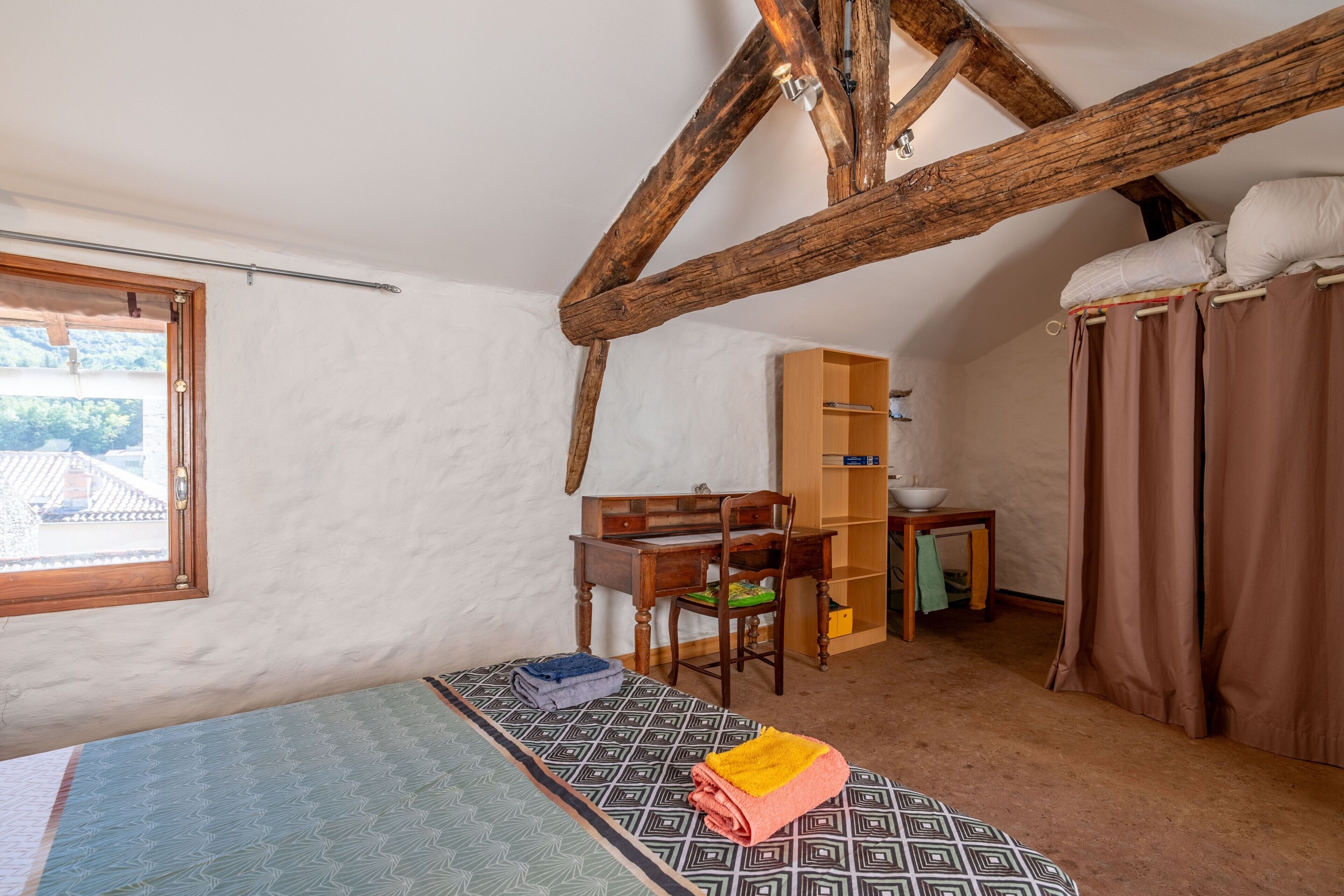 Un dormitorio con cama, escritorio, silla, armario y ventana.