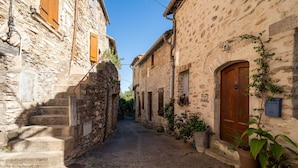 Un estrecho callejón adoquinado flanqueado por edificios de piedra con puertas y contraventanas de madera.
