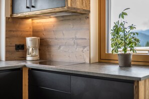 Eine Küche mit Kaffeemaschine, Holzschränken und einem Fenster mit Blick.