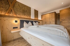Une chambre à coucher avec une tête de lit en bois, un lit avec une literie à carreaux, une table de chevet et des armoires en bois.