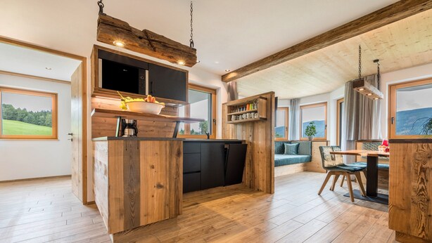 Eine moderne Küche mit Holzschränken, einer eingebauten Mikrowelle und einem Essbereich mit Tisch und Stühlen.