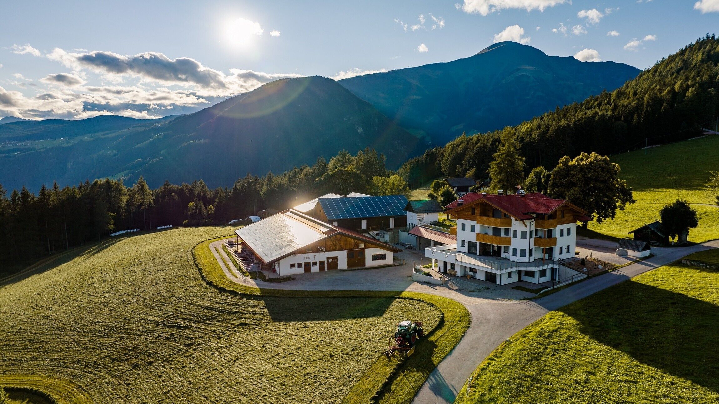 Un edificio moderno con un tetto solare, immerso in un prato curato e con le montagne sullo sfondo.