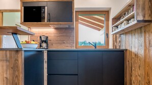 A modern kitchen with a built-in microwave, coffee maker, and wooden cabinetry. - Holiday Apartment "Forchnerhof 4" with Mountain View, 2 Private Terraces & Wi-Fi (Terenten)