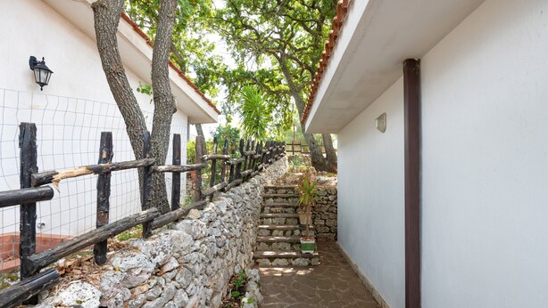 Un étroit sentier de pierres, bordé d’un mur de pierres et d’une clôture en bois, mène à un escalier.
