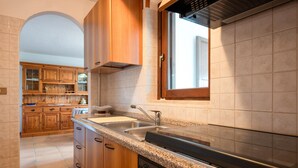 Une cuisine avec des meubles en bois, un plan de travail en granit, un évier en acier inoxydable et une fenêtre au-dessus de l’évier.