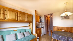 Una habitación acogedora con una cama de madera, una mesa de comedor y una zona de cocina.
