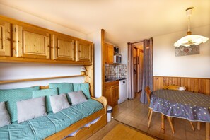 Una habitación acogedora con una cama de madera, una mesa de comedor y una zona de cocina.