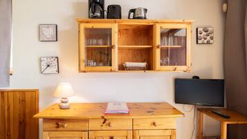Een houten kast met glazen deuren, een televisie en een lamp op een houten tafel.