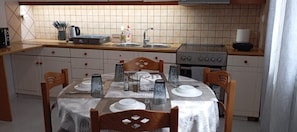Ett kök med ett matbord för fyra personer, en spis och ett diskho.