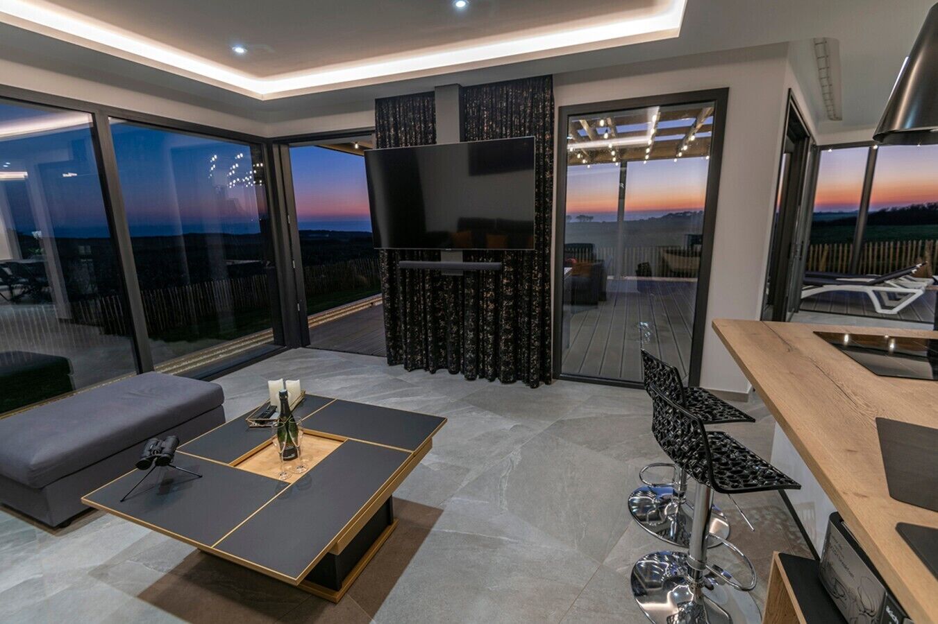 A modern living room with a large TV, a fireplace, and a balcony with a scenic view.