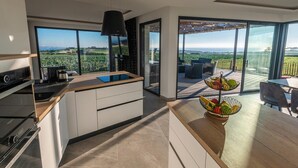 Eine moderne Küche mit einer großen Kochinsel, ein Essbereich mit Blick und ein Balkon mit Sitzgelegenheit.