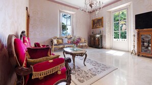 A spacious room with a chandelier, a sofa set, a television, and a large window.