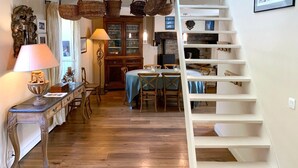 Ein Essbereich mit Holztisch und Stühlen, einer Lampe, einem Schrank mit Gläsern und einer Treppe.