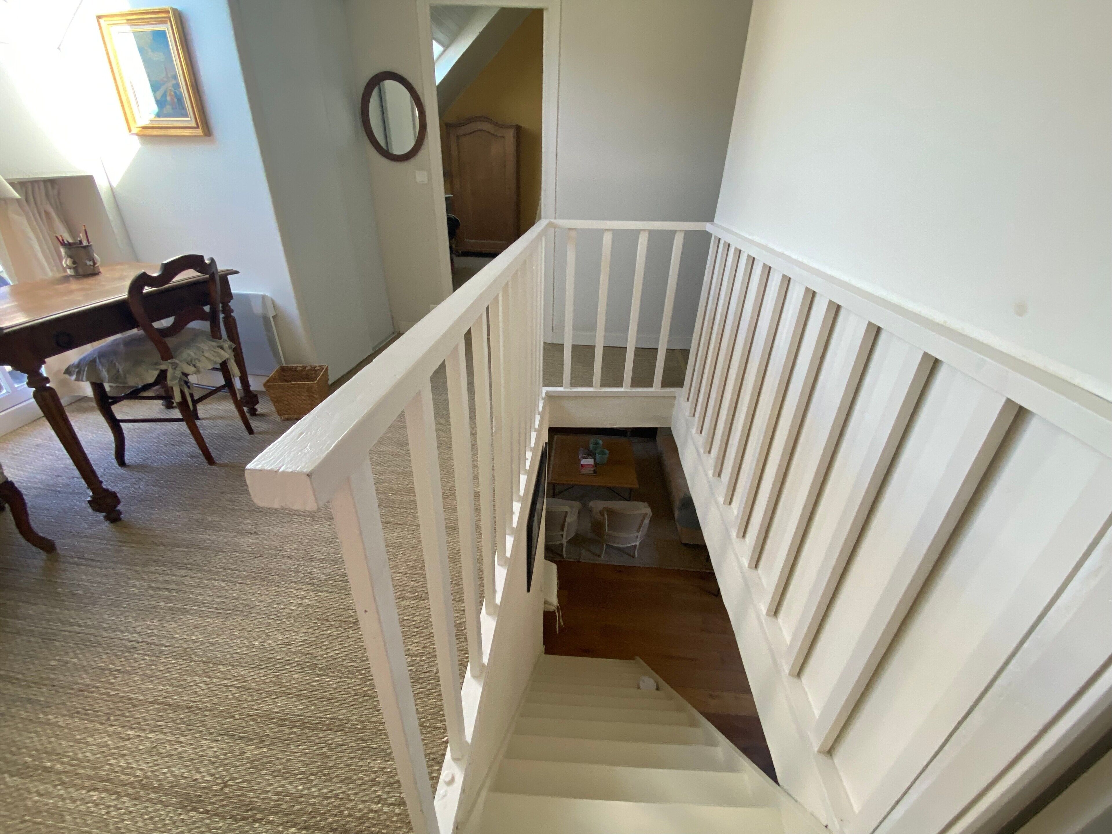 Un escalier avec des rampes blanches menant à un niveau inférieur.