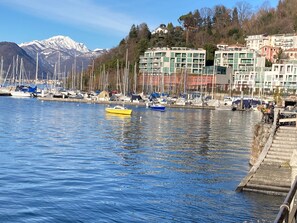 Ein Yachthafen mit Booten, ein Berg im Hintergrund und Gebäude entlang der Küste.