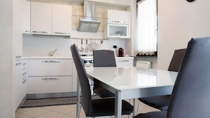 Una cocina moderna con armarios blancos, microondas y una mesa de comedor con sillas.