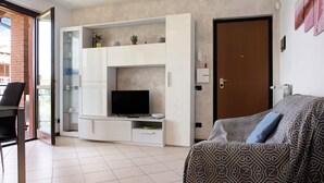 Una sala de estar moderna con un televisor de pantalla plana, un sofá, un aparador de vidrio y una puerta.