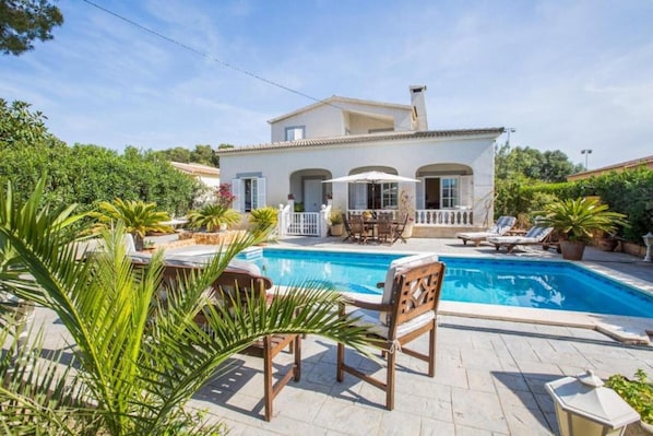 A villa with a swimming pool, outdoor furniture, and lush greenery. - Villa 'Can Navarro' with Private Pool, Private Terrace and Wi-Fi (Llucmajor)