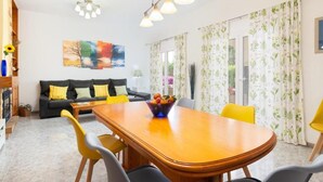 Een eetgedeelte met een houten tafel, gele stoelen en een fruitschaal.