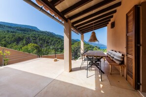 A balcony with a table and chairs, a hanging light fixture, and a view of a mountainous landscape. - Holiday Home 'Dream Property In Alconasser' with Sea View, Pool, Terrace & Wi-Fi (Sóller)