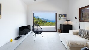 A modern living room with a TV, a chair, a sofa, a desk, and a view of the sea. - Holiday Home 'Dream Property In Alconasser' with Sea View, Pool, Terrace & Wi-Fi (Sóller)