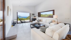 A modern living room with a large window, a sofa, a coffee table, and a view of the sea. - Holiday Home 'Dream Property In Alconasser' with Sea View, Pool, Terrace & Wi-Fi (Sóller)