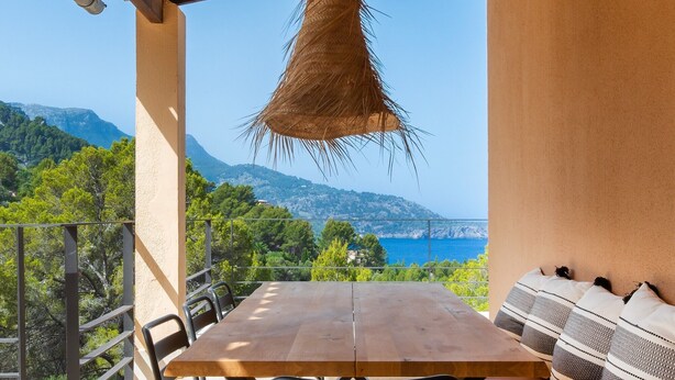 A wooden table with chairs and a bench, a hanging light fixture, and a view of a coastal landscape. - Holiday Home 'Dream Property In Alconasser' with Sea View, Pool, Terrace & Wi-Fi (Sóller)