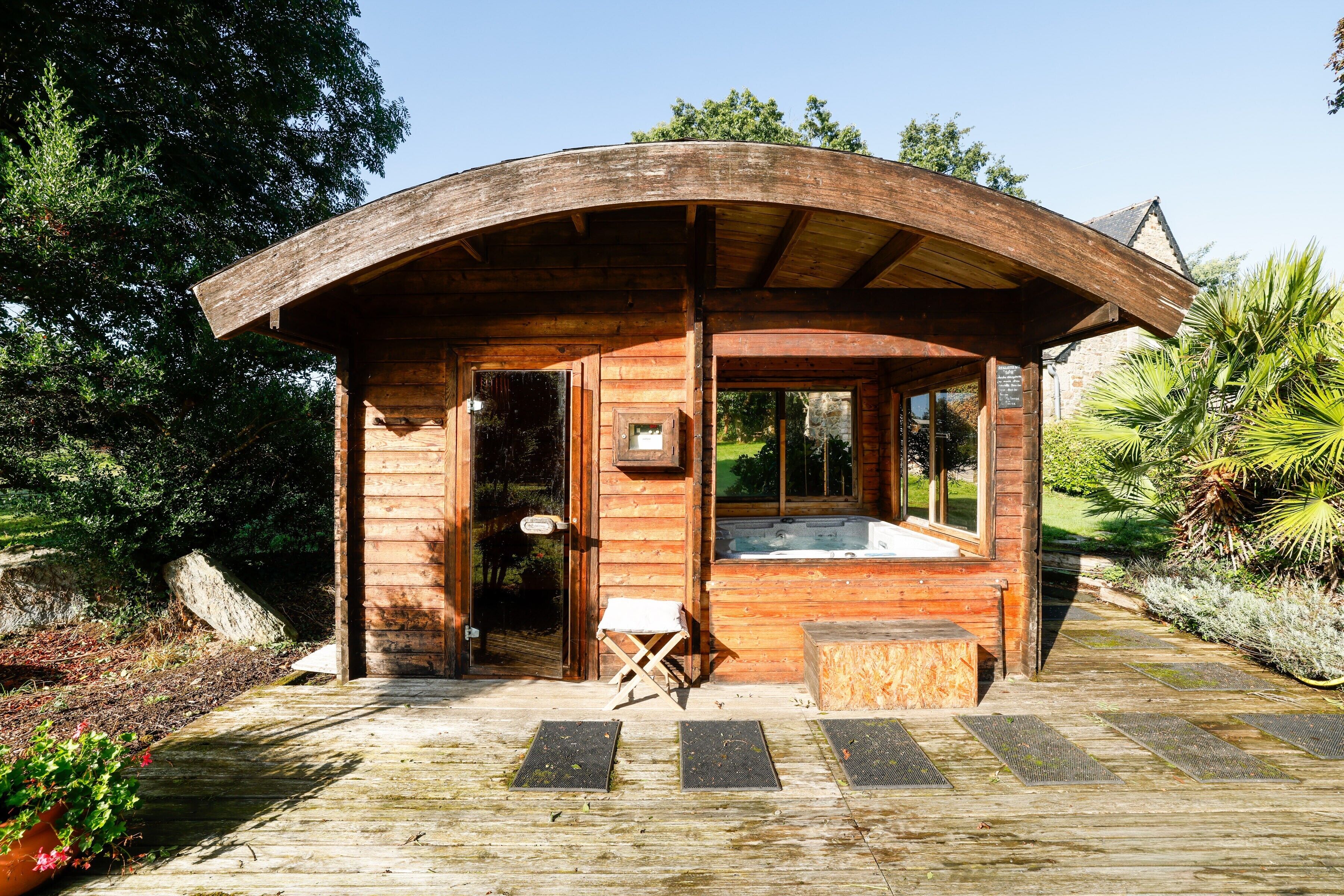 Une cabane en bois avec un toit incurvé, un jacuzzi et un petit coin salon.