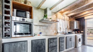 A modern kitchen with built-in appliances, a washing machine, and a large window.