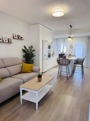 A modern living room with a sofa, coffee table, and dining area with chairs.