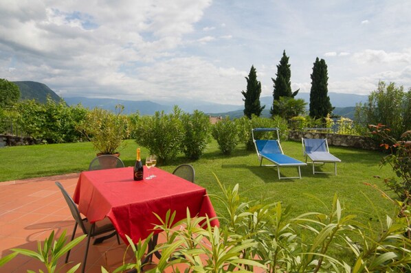 A patio with a red table, two blue lounge chairs, and a bottle of wine. - Apartment 'Aurora' with Mountain View, Private Terrace and Wi-Fi (Kaltern)
