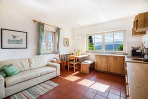 A cozy living room with a sofa, a dining table, and a kitchen area with a view. - Apartment 'Aurora' with Mountain View, Private Terrace and Wi-Fi (Kaltern)