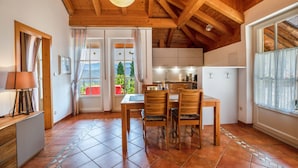 Una cocina con vigas de madera, una mesa de comedor con sillas y vistas al exterior.