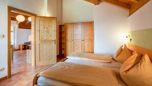 Un dormitorio con dos camas, un armario de madera y una puerta que da a otra habitación.
