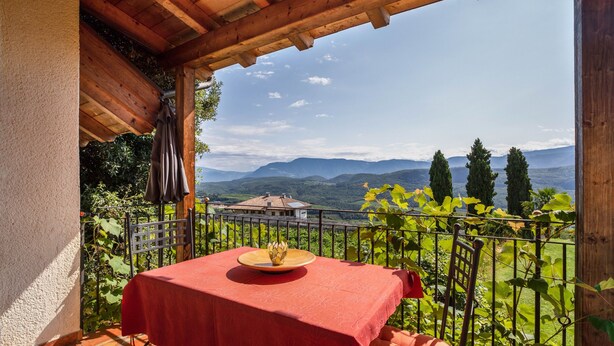 Una terraza con una mesa lista para comer, vistas a las montañas y una pérgola de madera.